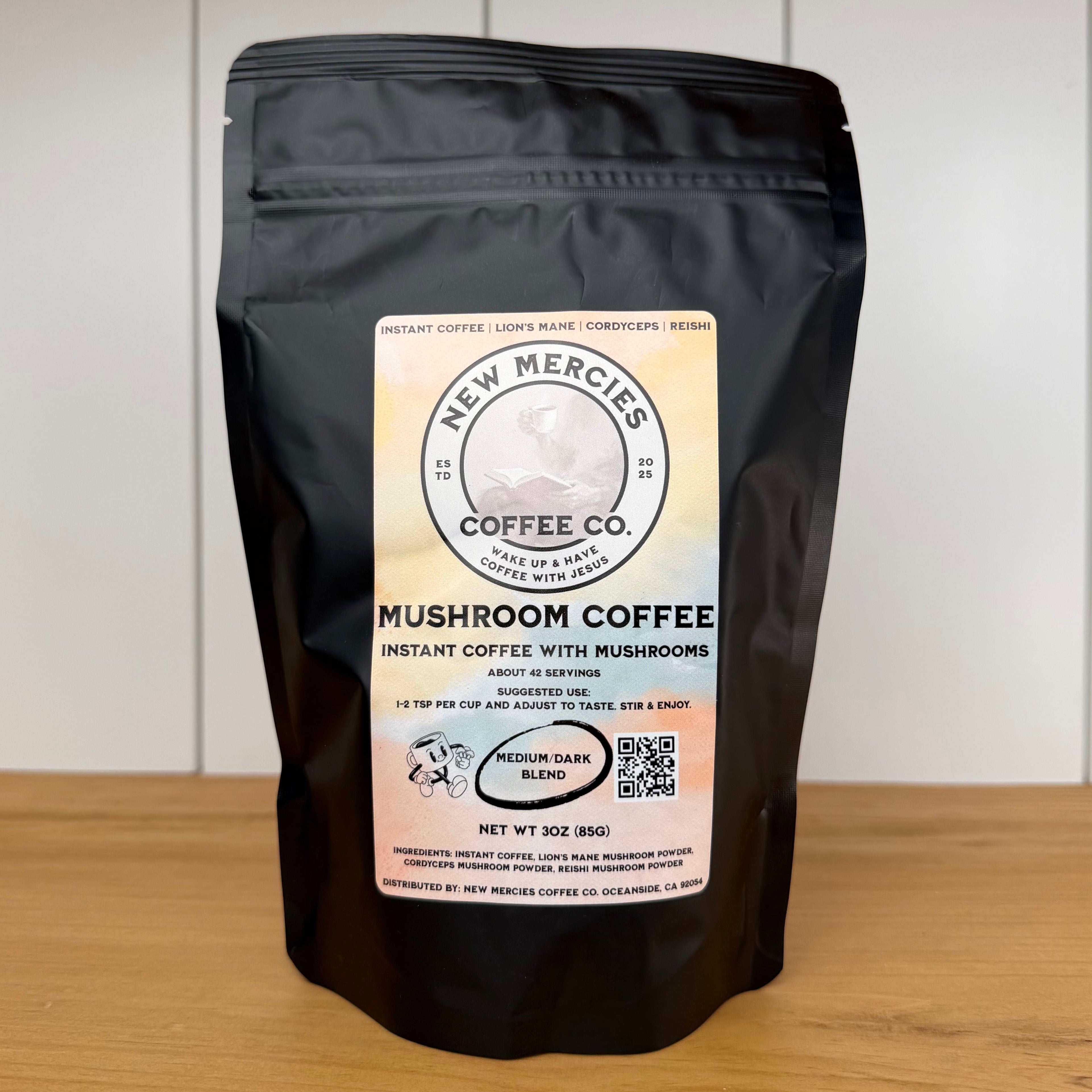Black coffee bag with 'New Mercies Coffee Co.' label on a wooden surface